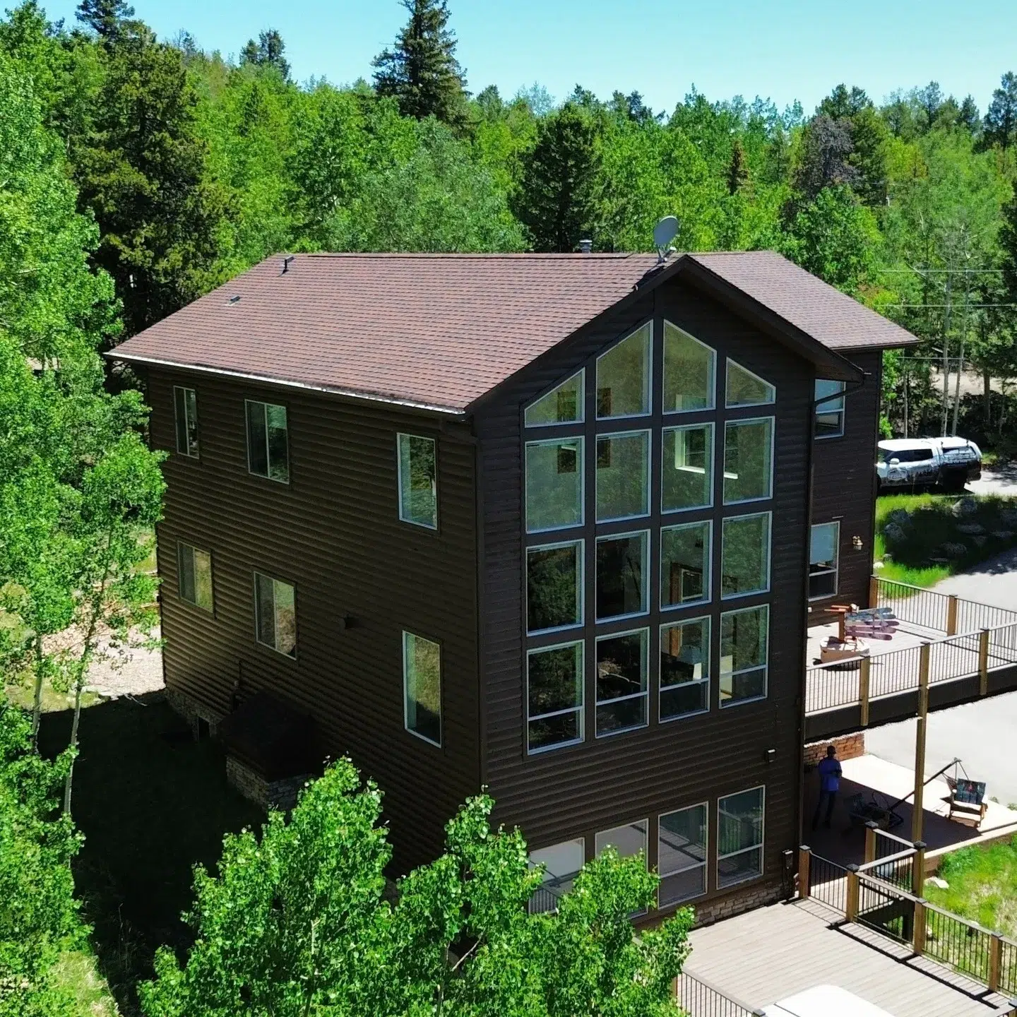 Black Painted Modern Residential Home Modern black-painted residential home with large window wall, mauve roof, and multi-level deck in Littleton forest setting.