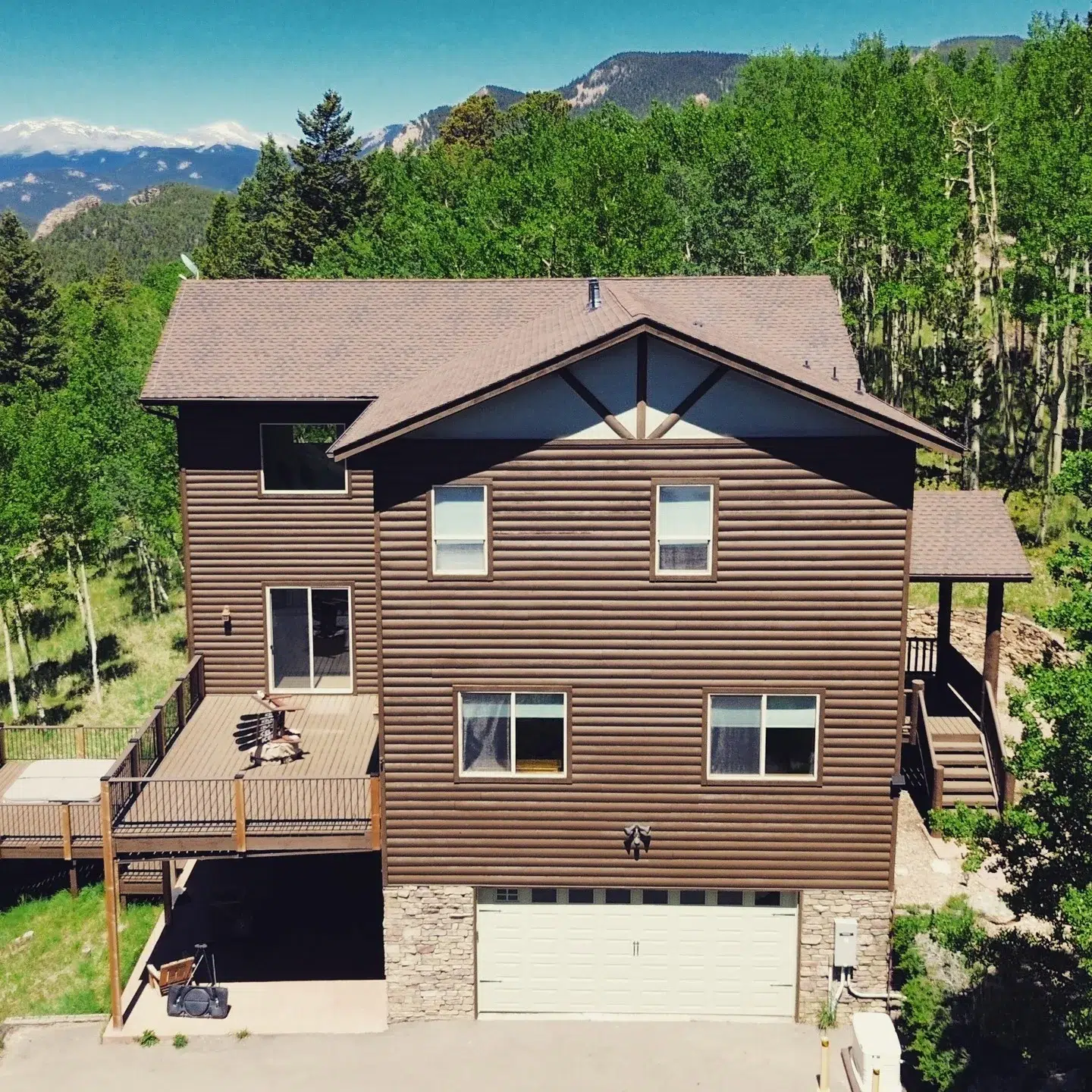 Brown Log Siding Home Exterior Brown horizontal log-style siding on multi-level residential home with dark roof, stone garage base, and wooden decks in