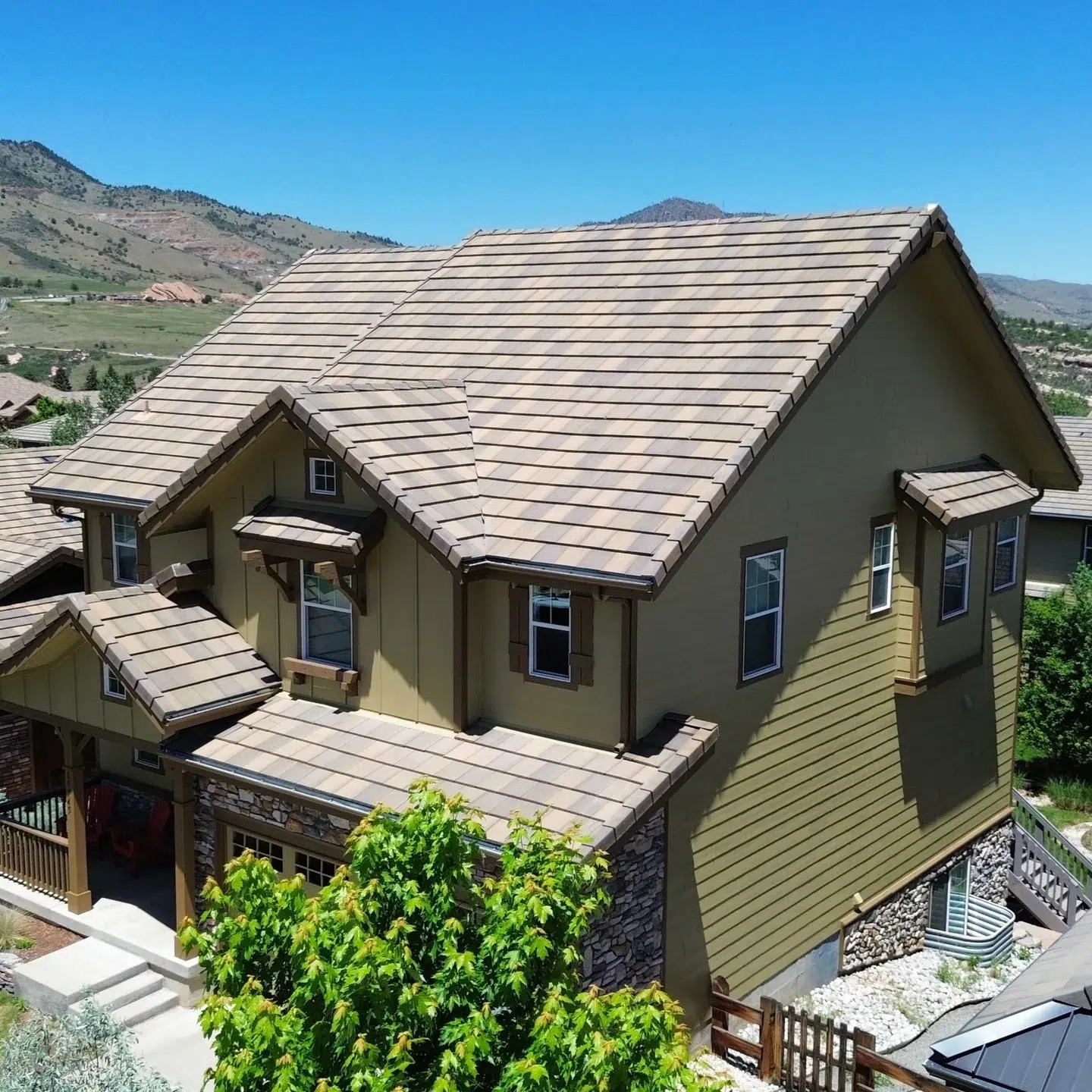 Sage Green Two-Story Mountain Home Sage green two-story residential home with taupe roof, stone foundation, and cream-painted horizontal siding in Southwest